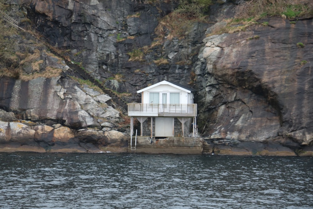 a white house sitting on top of a cliff next to a body of water