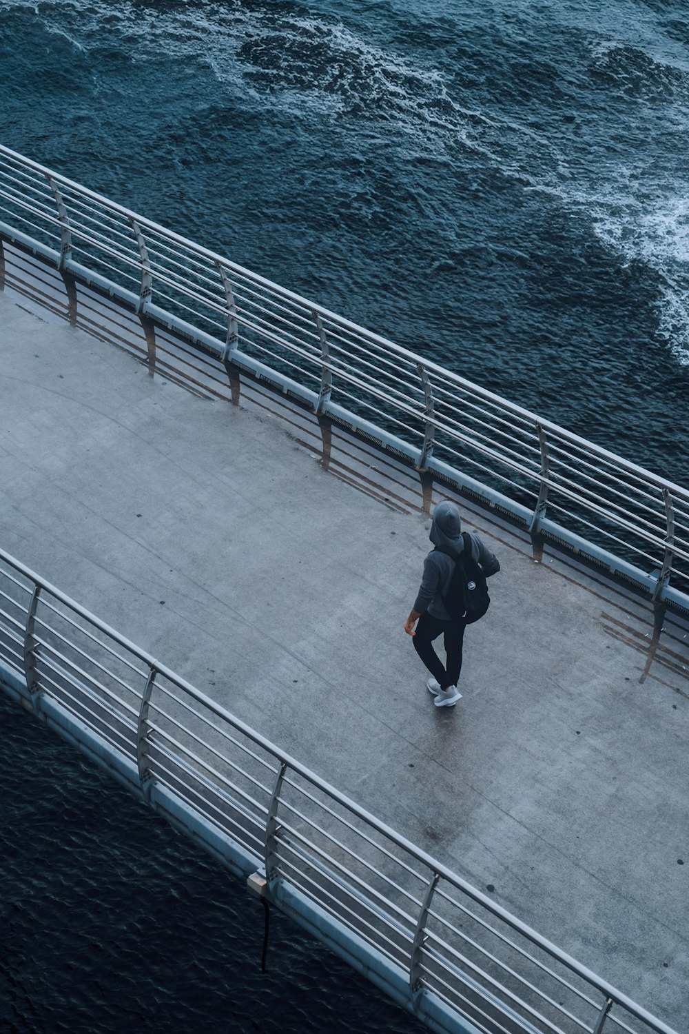 a person walking on a bridge over the water