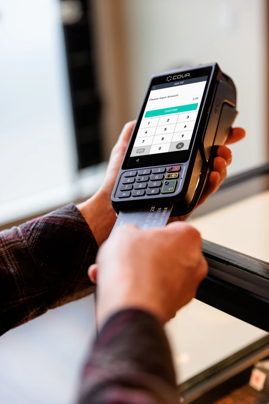 Printed merchant statement pages spread across a desk beside a calculator and pen