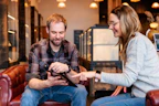 a man and a woman sitting on a couch looking at a tablet