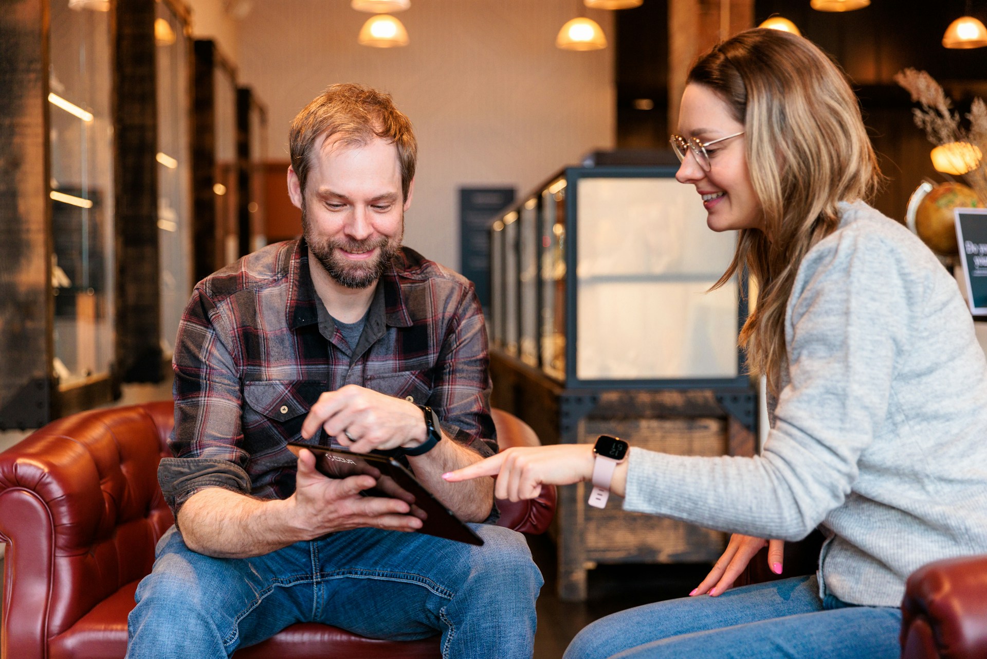 a man and a woman sitting on a couch looking at a tablet