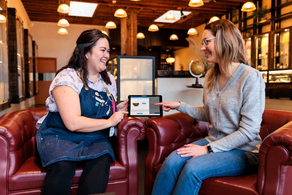 two women sitting on a couch talking to each other