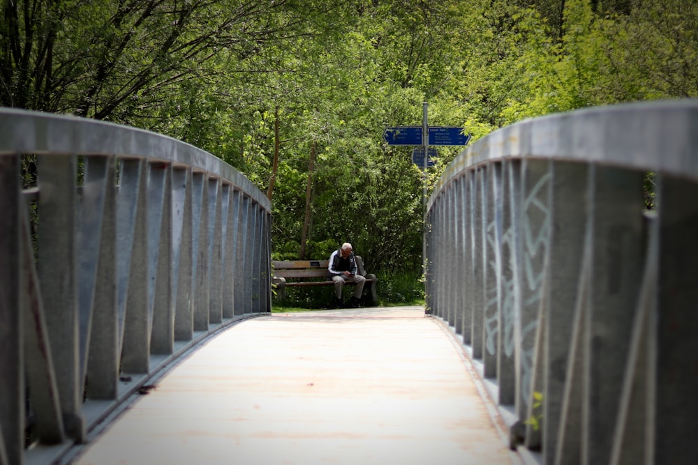 Ein Mann sitzt auf einer Bank auf einer Brücke