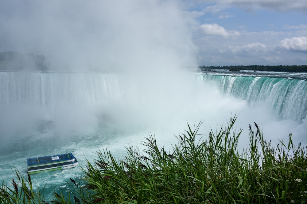 a boat in the water near a waterfall