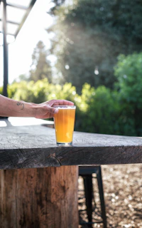 a glass of beer sitting on top of a wooden table