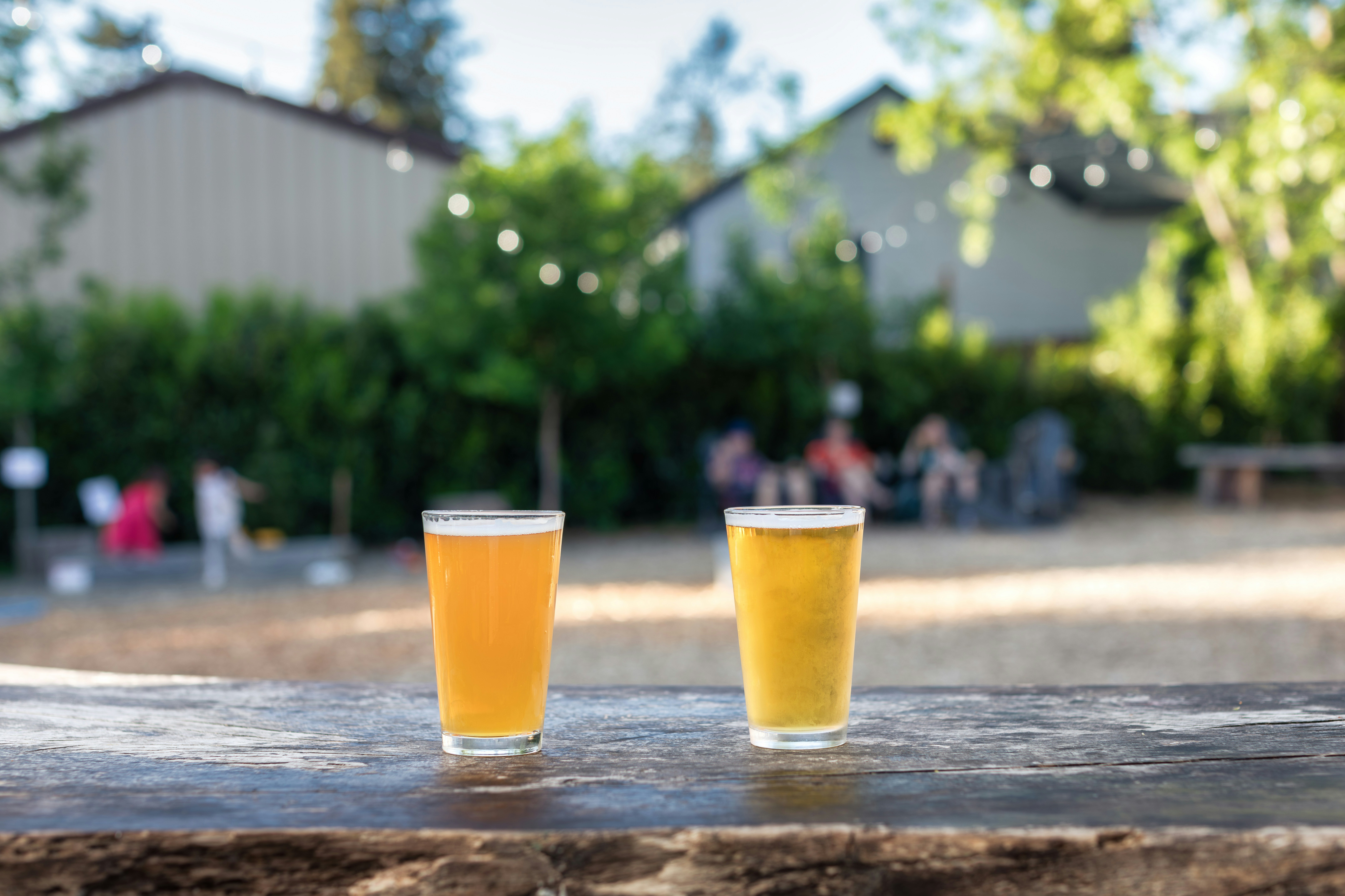 dois copos de cerveja sentados em cima de uma mesa de madeira