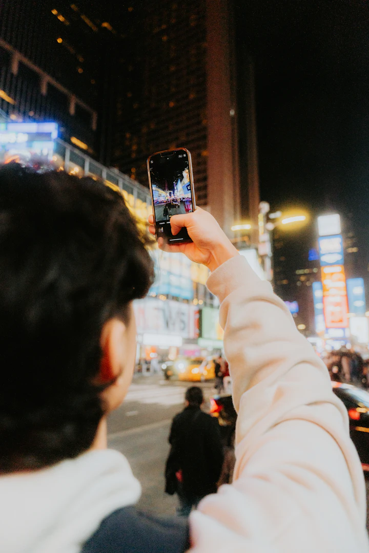 Eine reisende Person nutzt abends ihr Smartphone in der Stadt