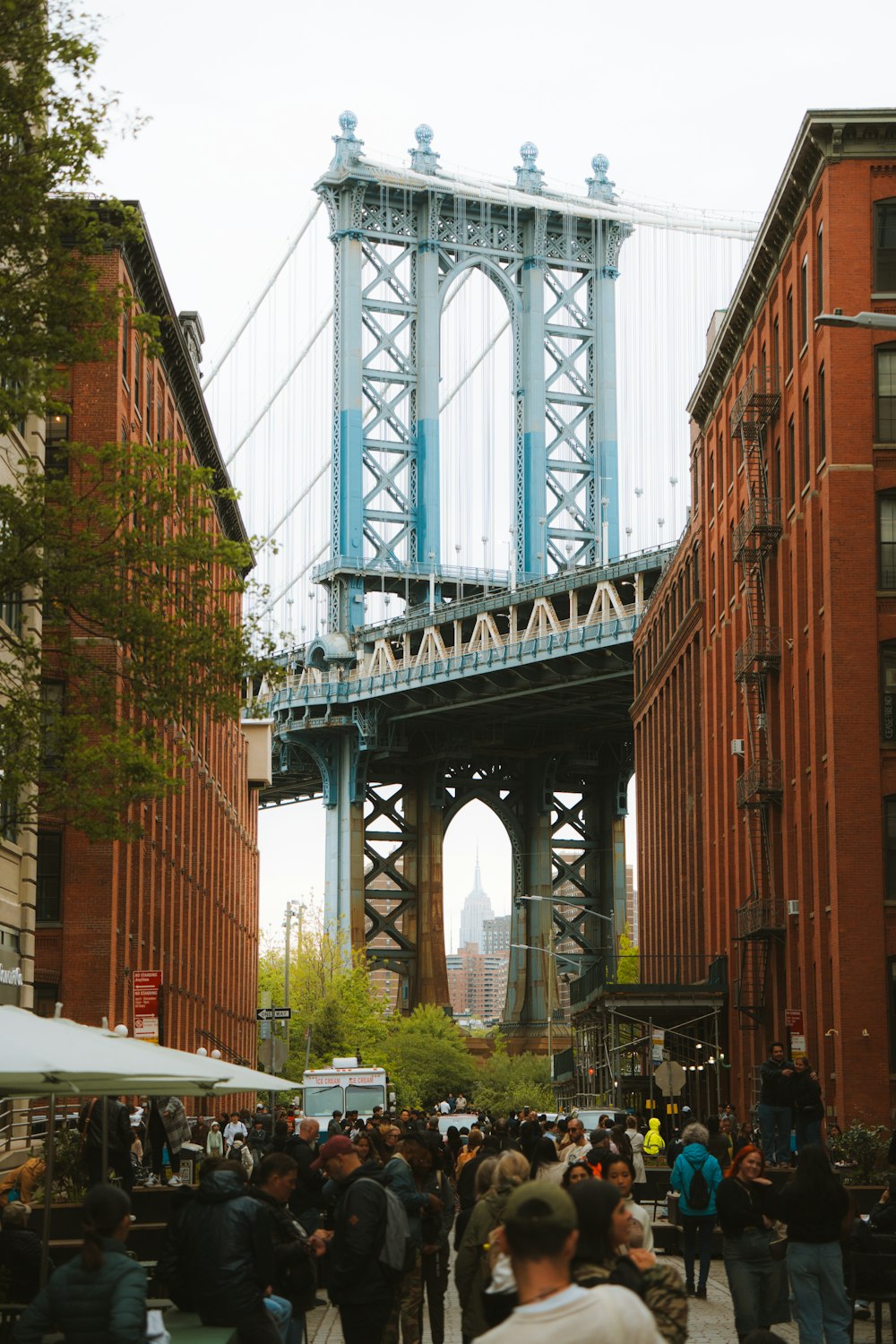 a group of people walking down a street under a bridge