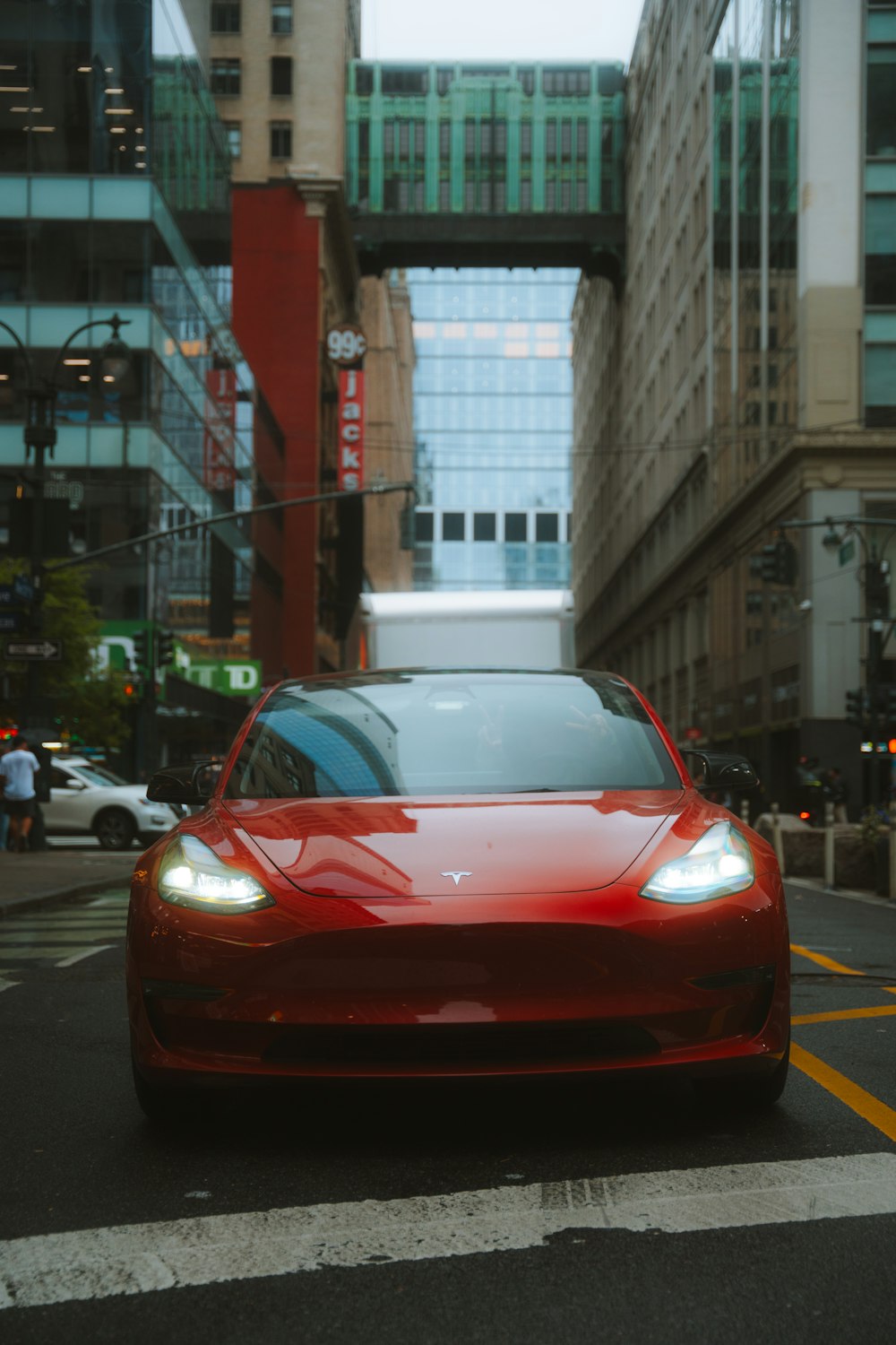 a red car driving down a street next to tall buildings