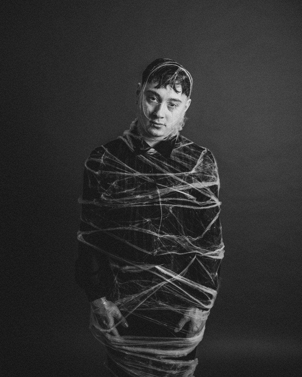 a black and white photo of a man wrapped in plastic wrap