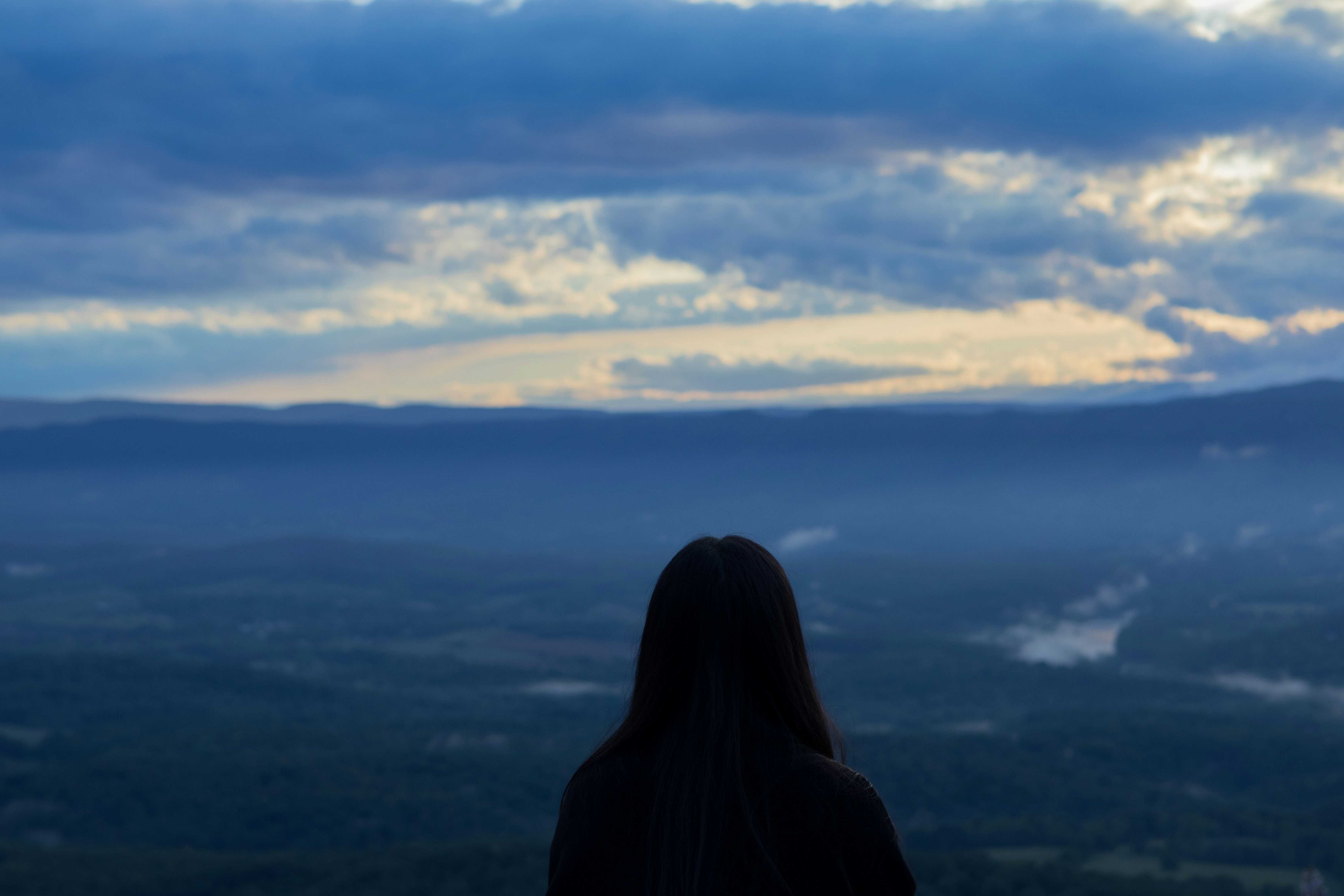 a woman looking out over a valley and mountains