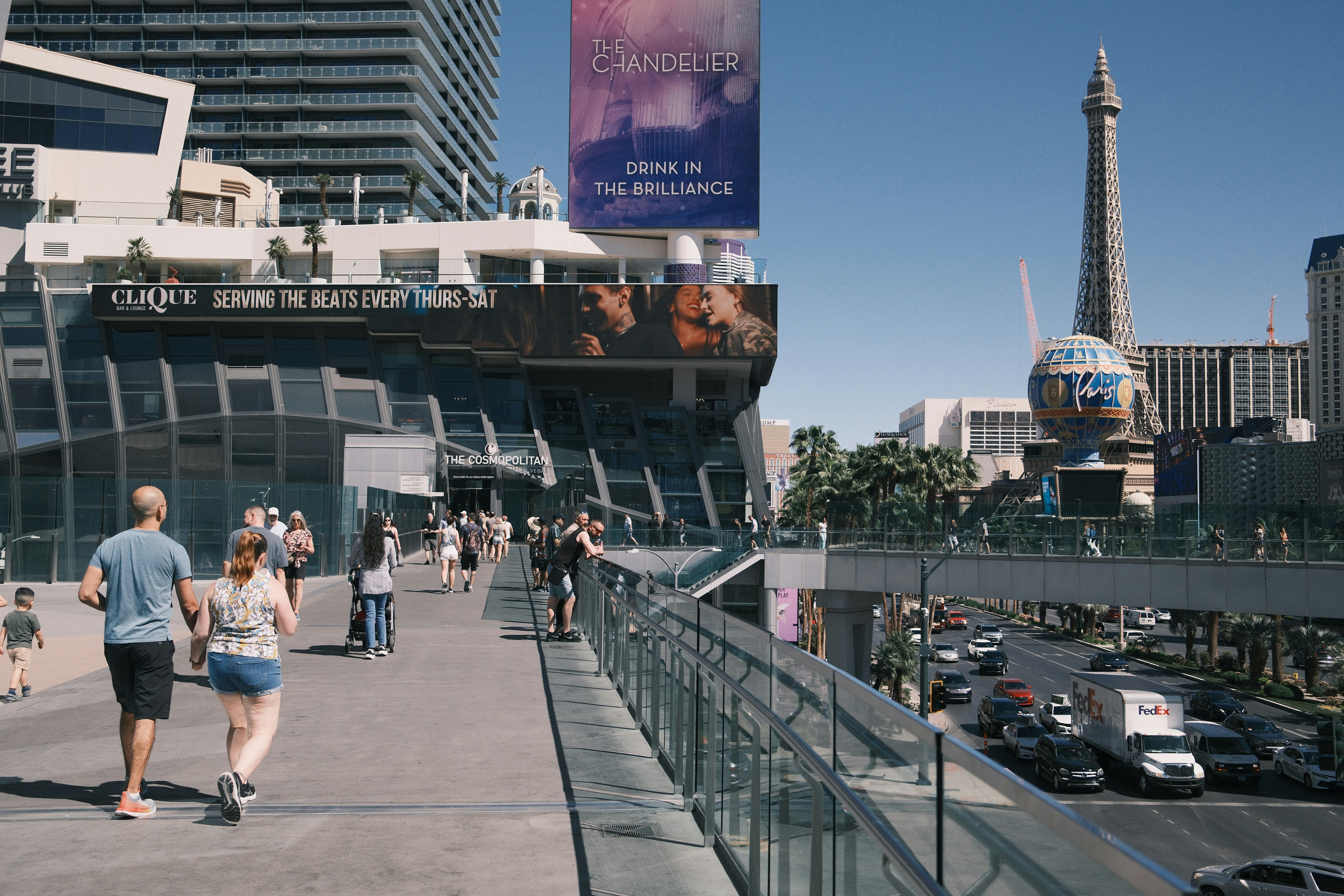 a group of people walking down a sidewalk next to tall buildings