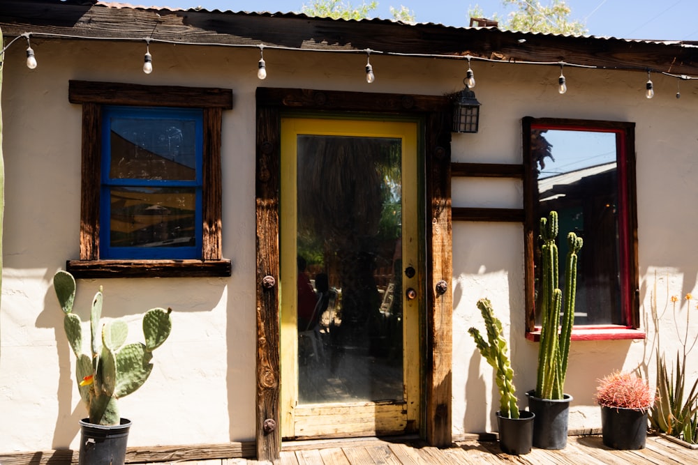a house with a yellow door and a cactus in front of it