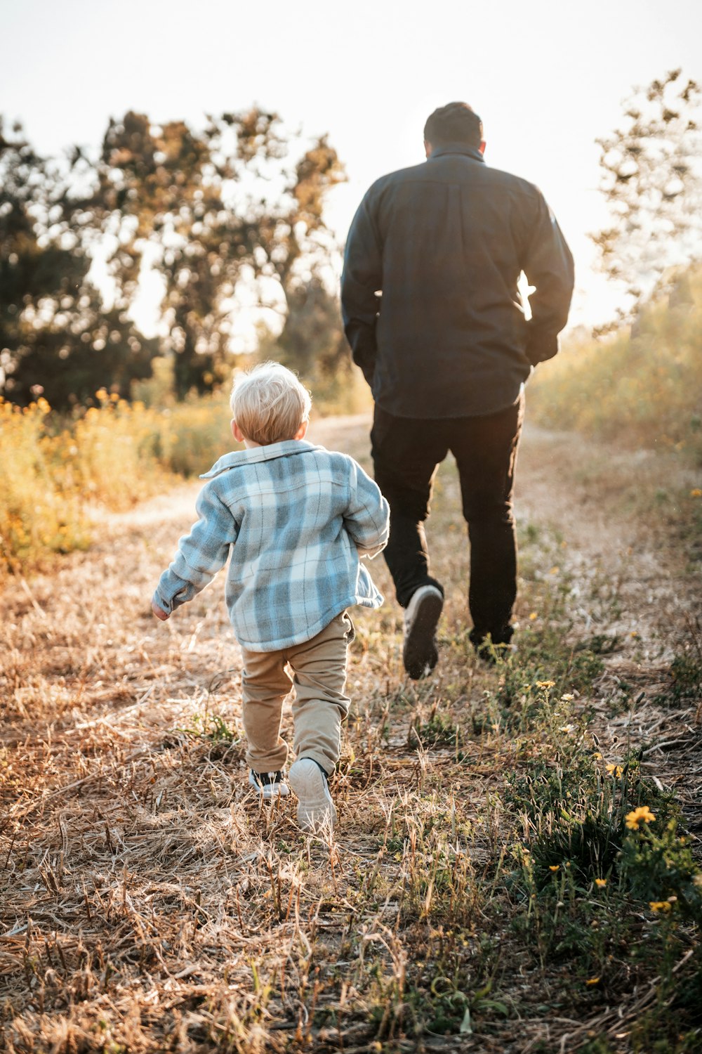 a man and a child walking down a dirt road