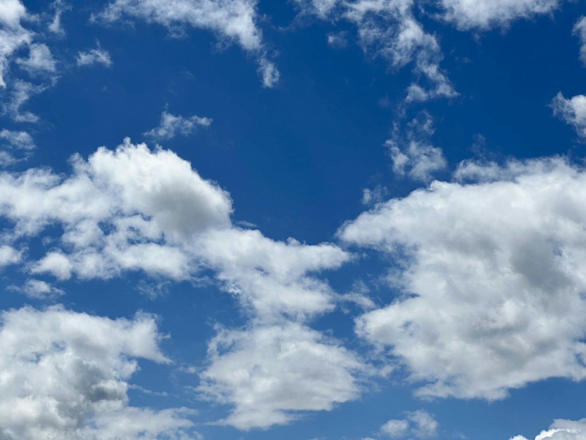 a blue sky with white clouds and a plane in the distance