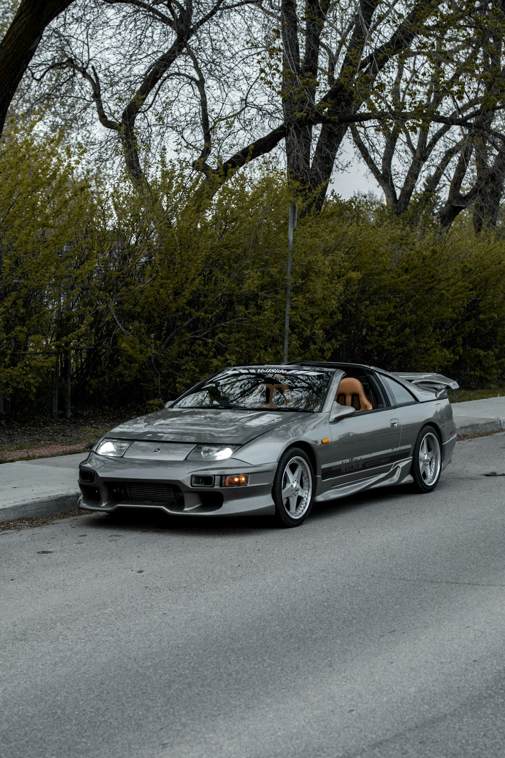 a silver sports car driving down a street