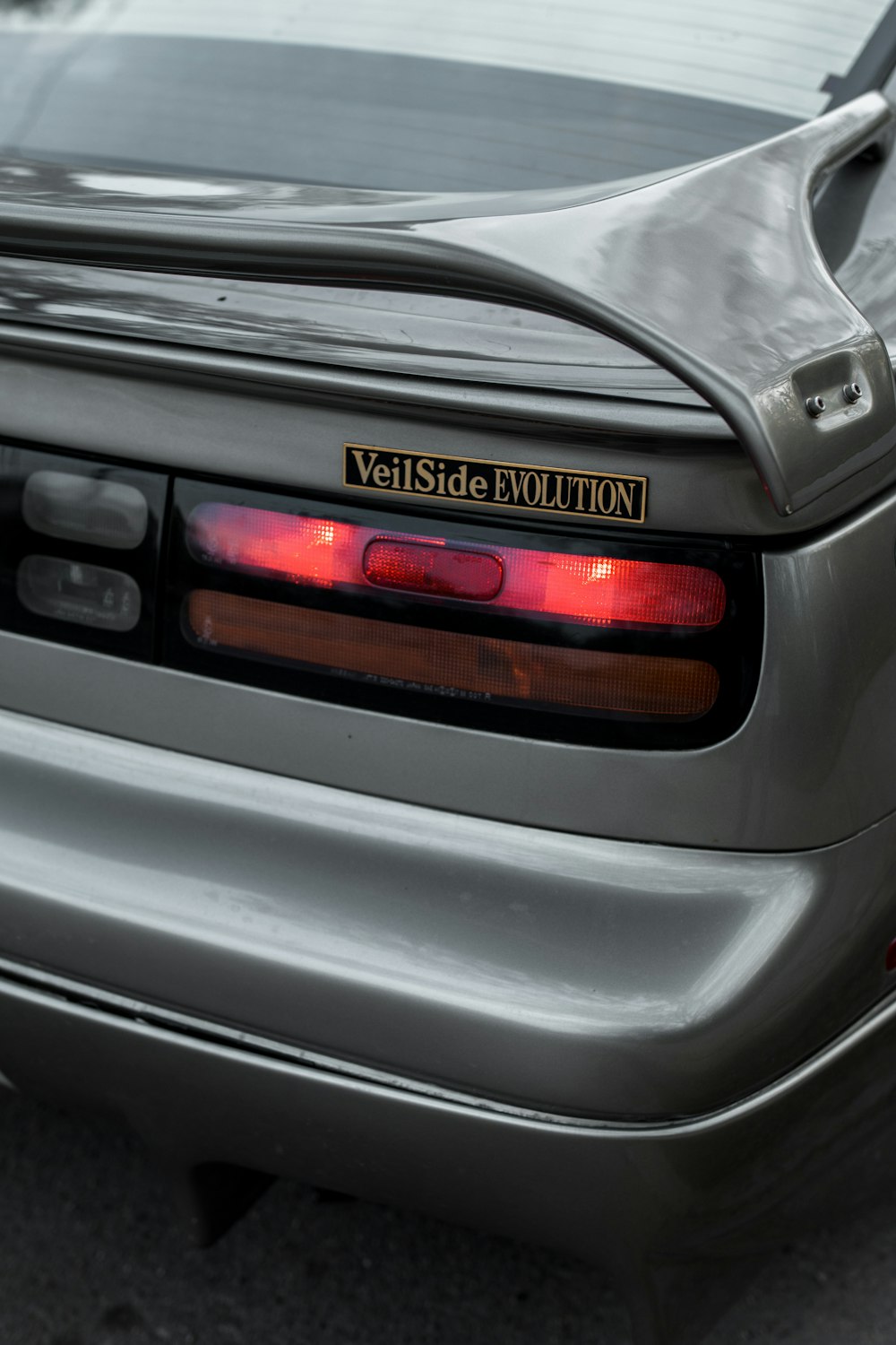 the back end of a silver car with a yellow sticker on it