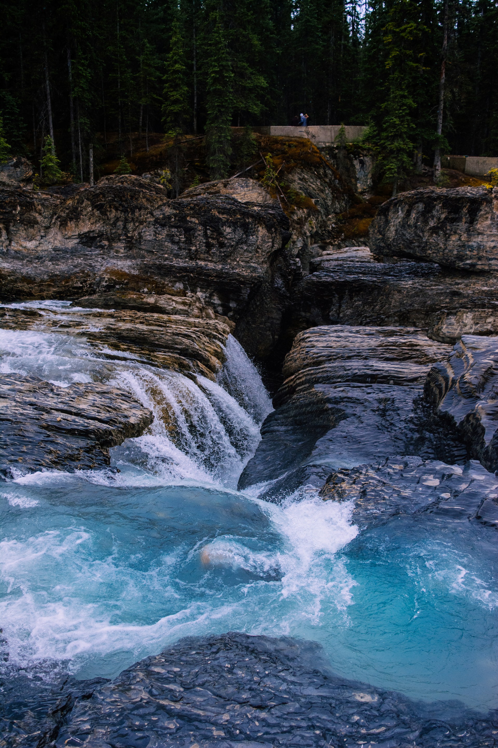 a man standing on top of a waterfall next to a river