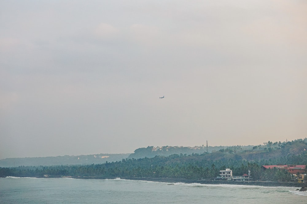 a plane is flying over the water near a beach