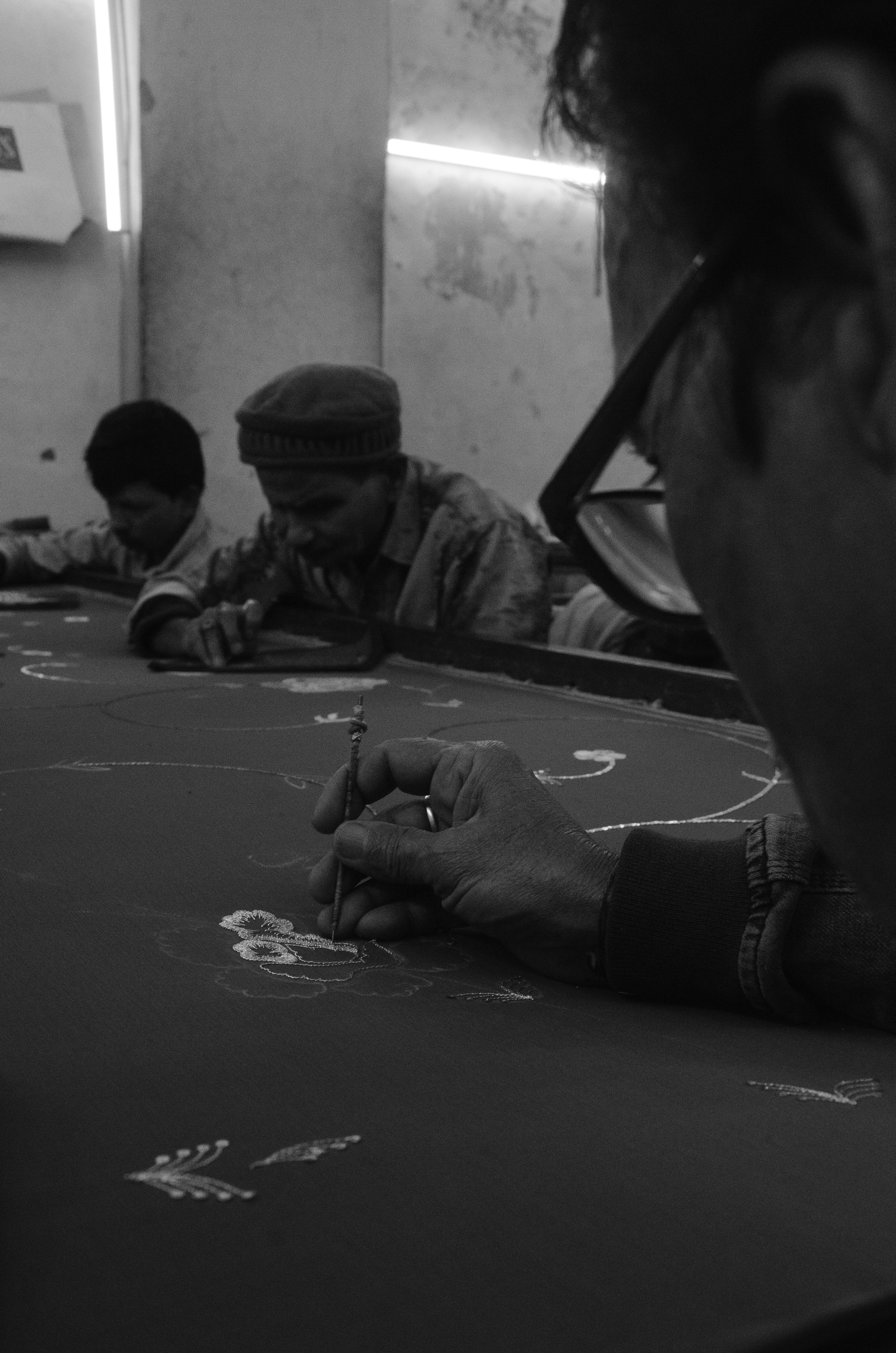 Artisan hands carefully stitching intricate embroidery on silk fabric in a sunlit workshop