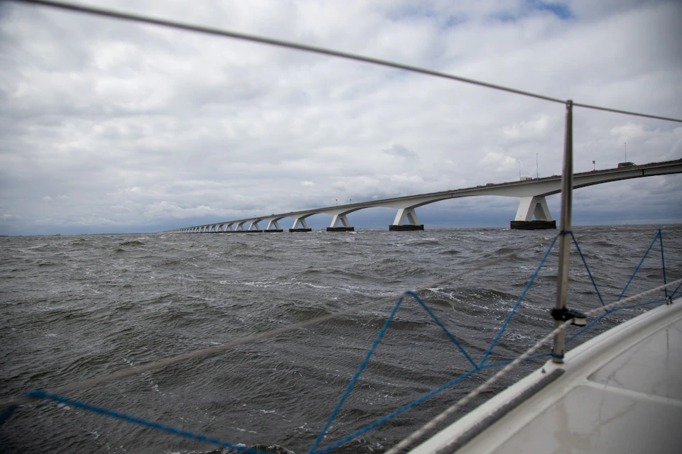 Large white bridge spans ocean, supported by multiple pillars and stretching into distance