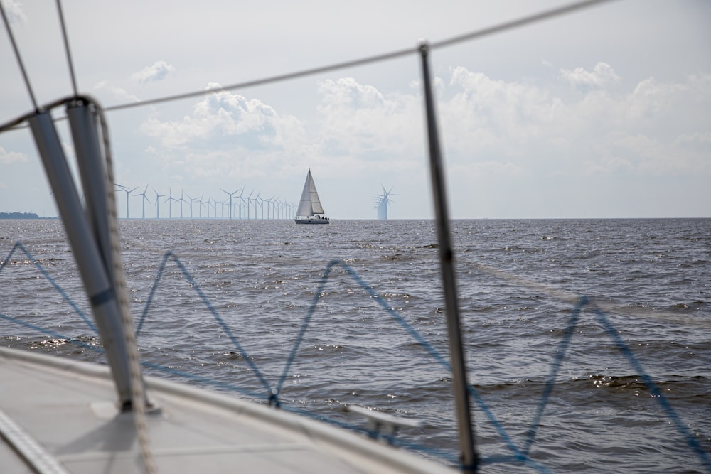 a sailboat in the ocean with wind mills in the background