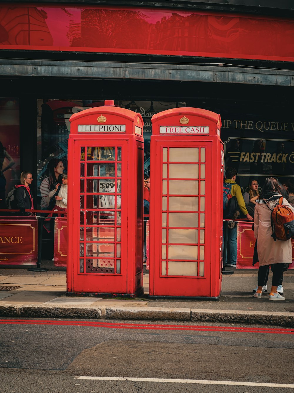 a couple of red telephone booths sitting on the side of a road