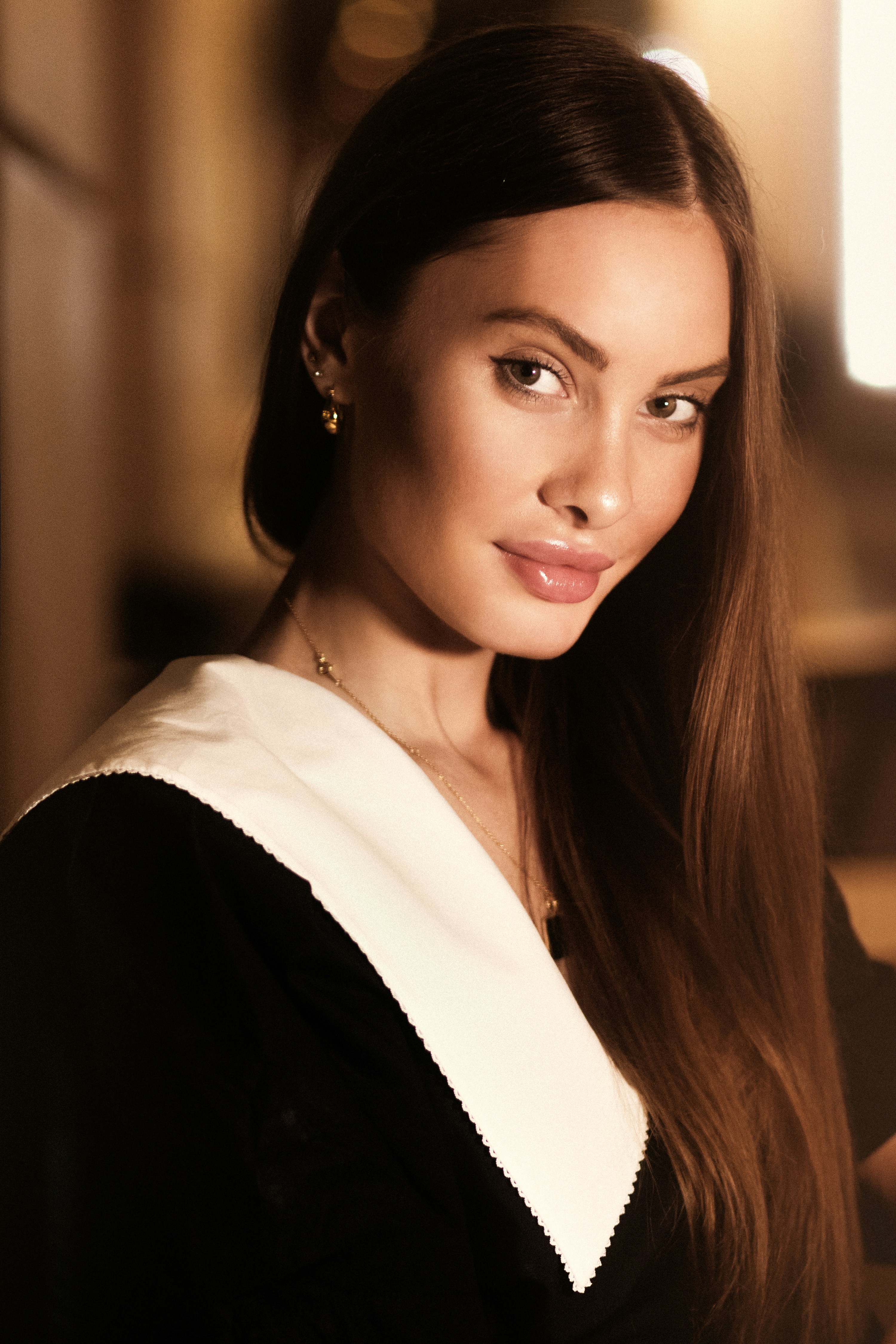 a woman with long brown hair wearing a black and white top