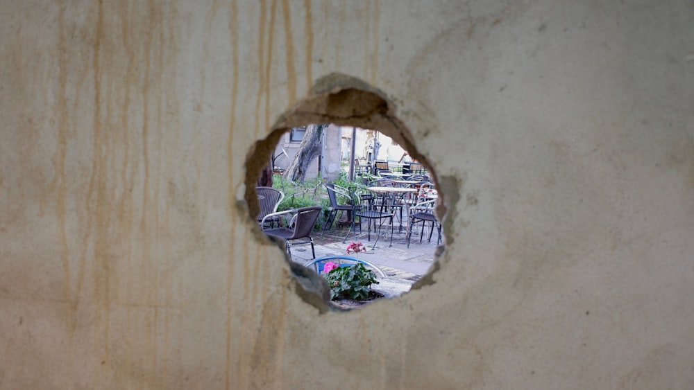 a hole in a wall with a table and chairs in the background