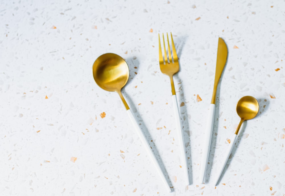 a group of gold colored spoons and forks