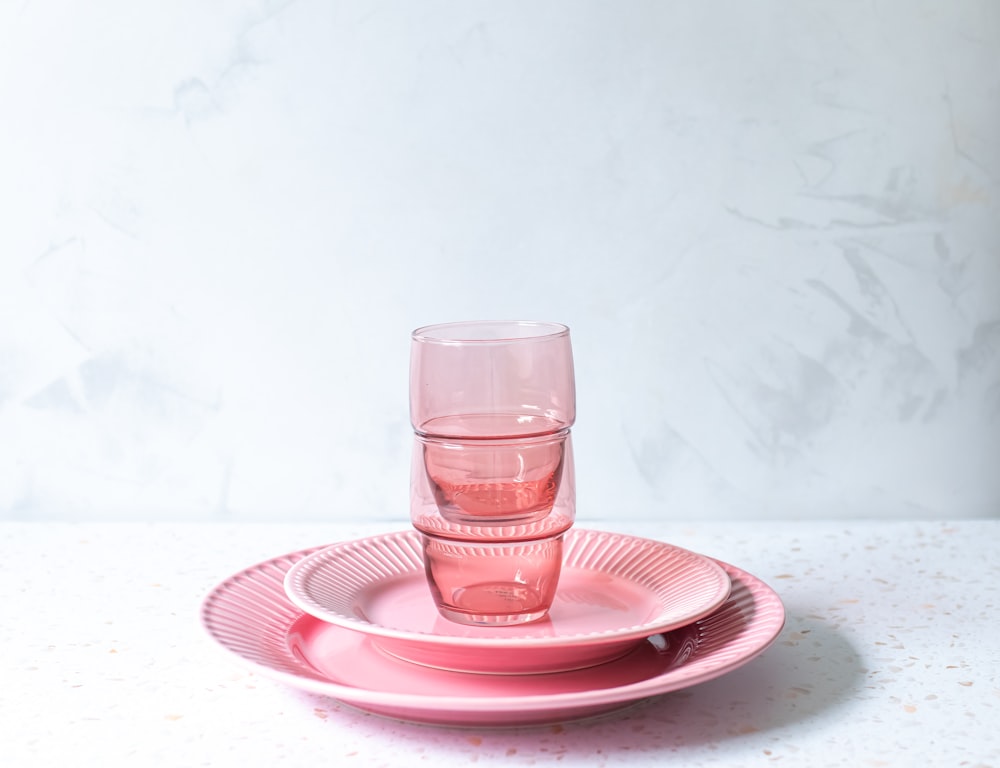 a stack of pink plates and cups on a table