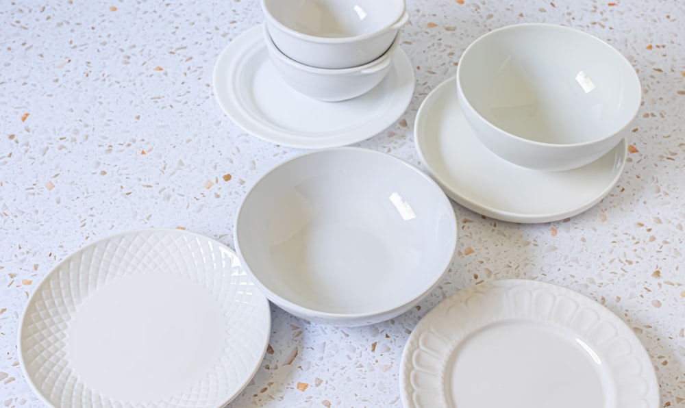 a table topped with white plates and bowls