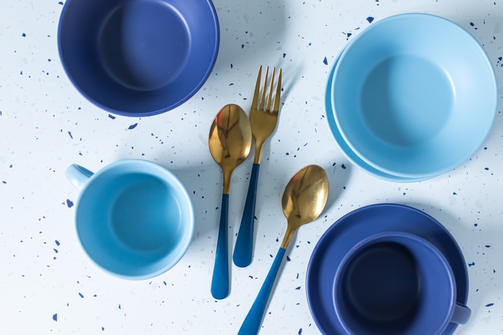 a table topped with blue dishes and gold utensils