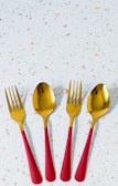 three red and gold spoons and two forks