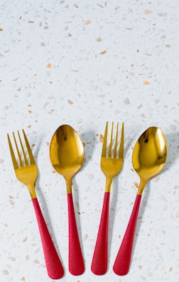 three red and gold spoons and two forks