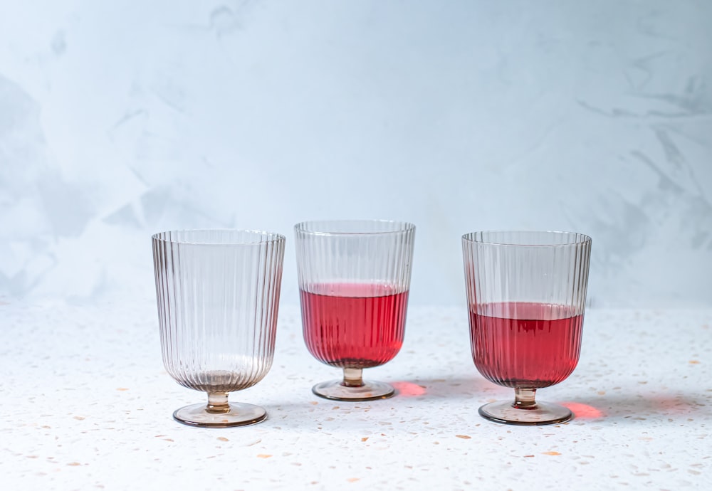 three glasses with red liquid in them on a table