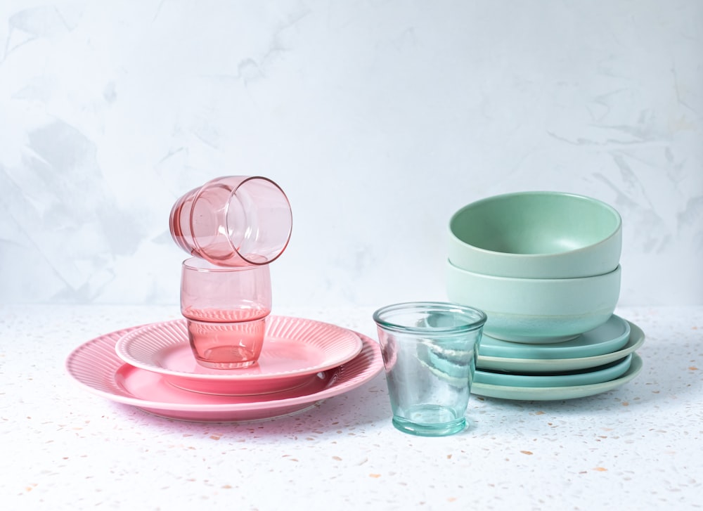 a stack of pink and green plates and cups