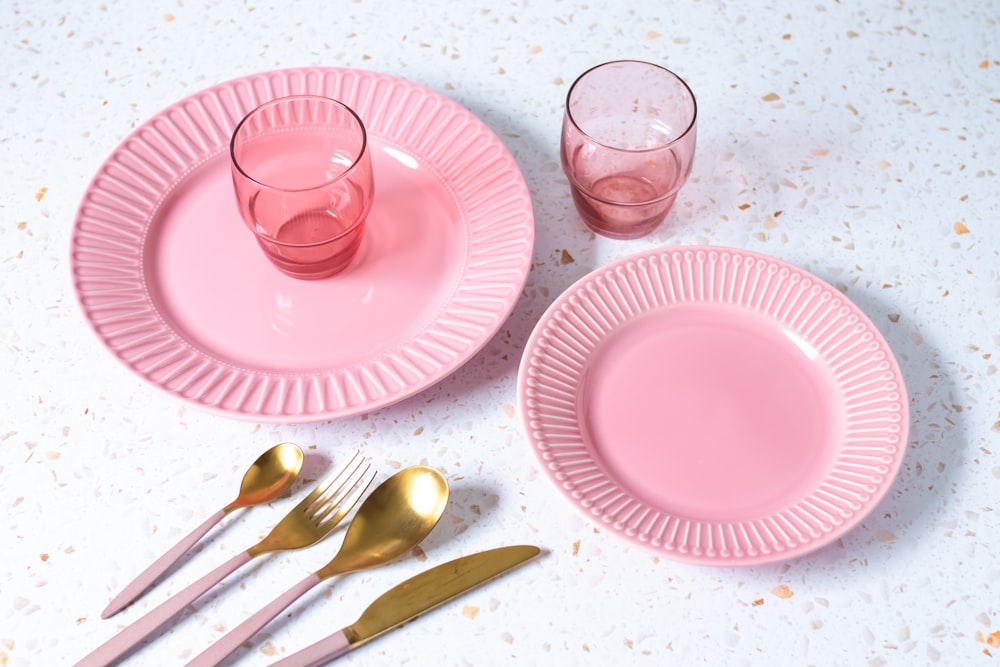 a pink table setting with utensils and a glass