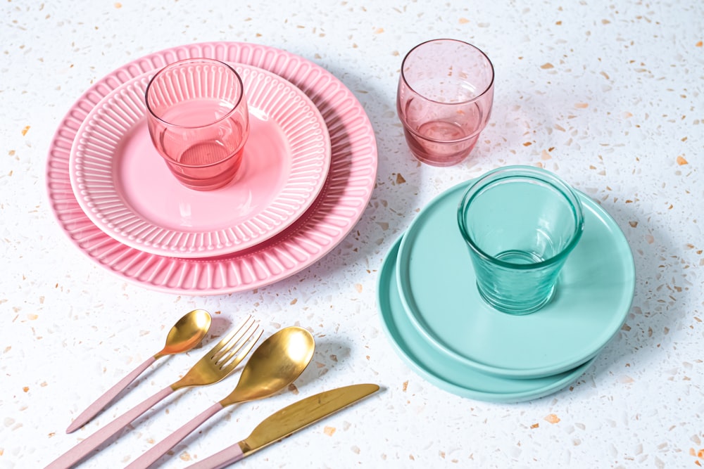 a table topped with pink and blue plates and silverware