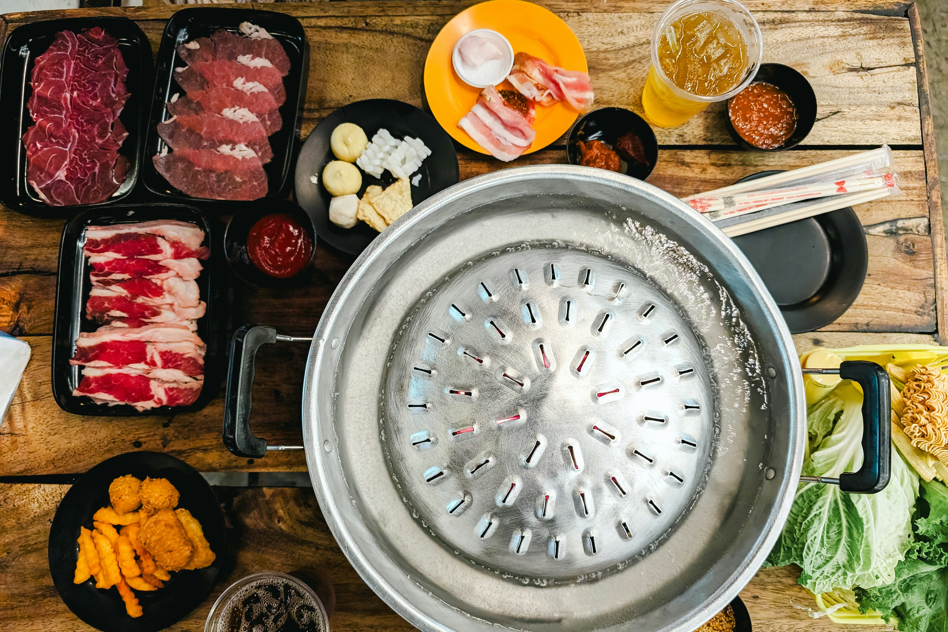 Korean barbecue table with dome grill, raw meats and sides