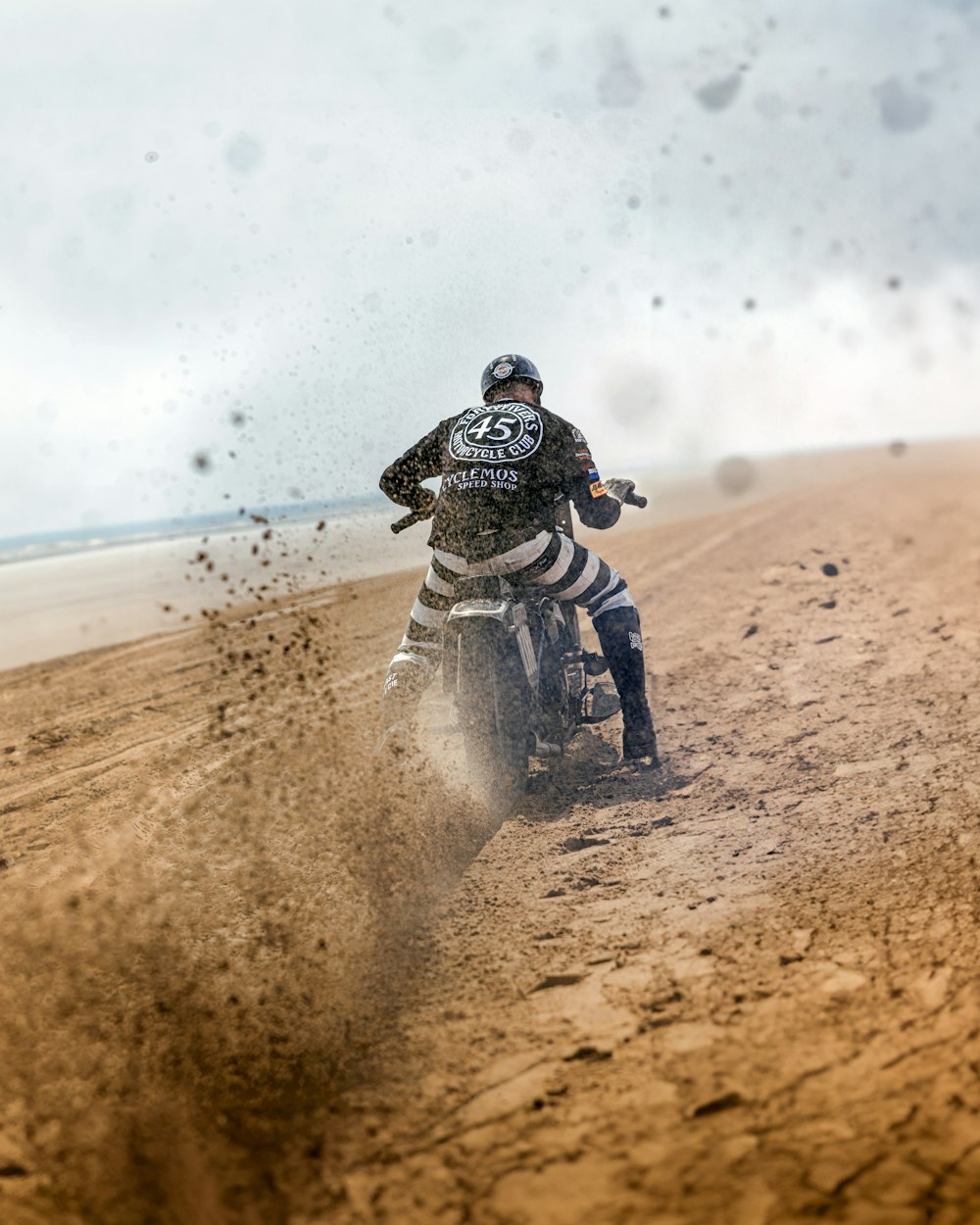 a man riding a dirt bike on top of a sandy beach
