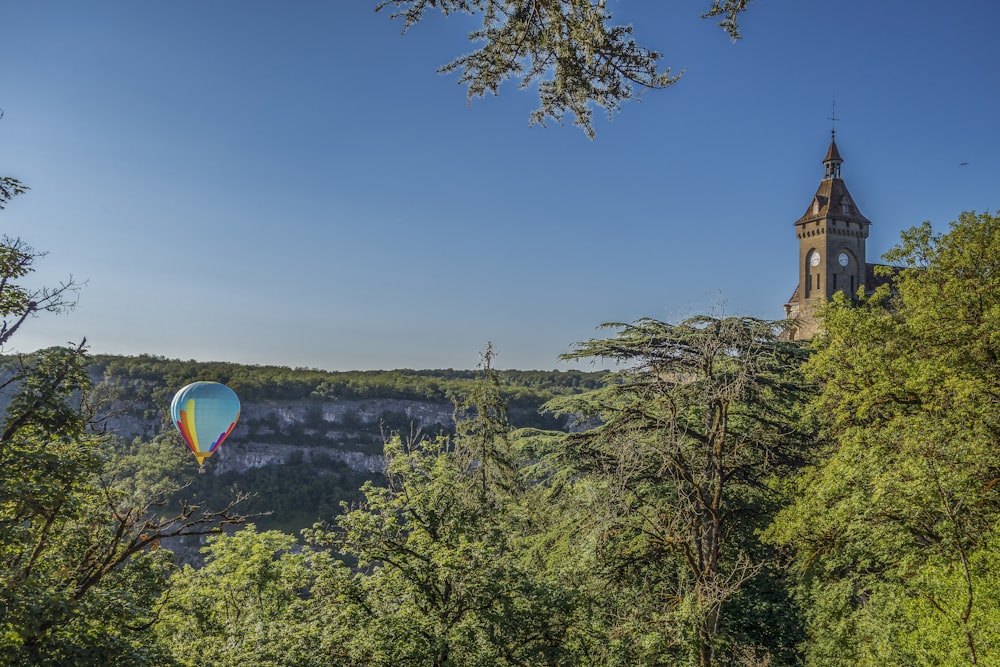 a hot air balloon flying over a lush green forest
