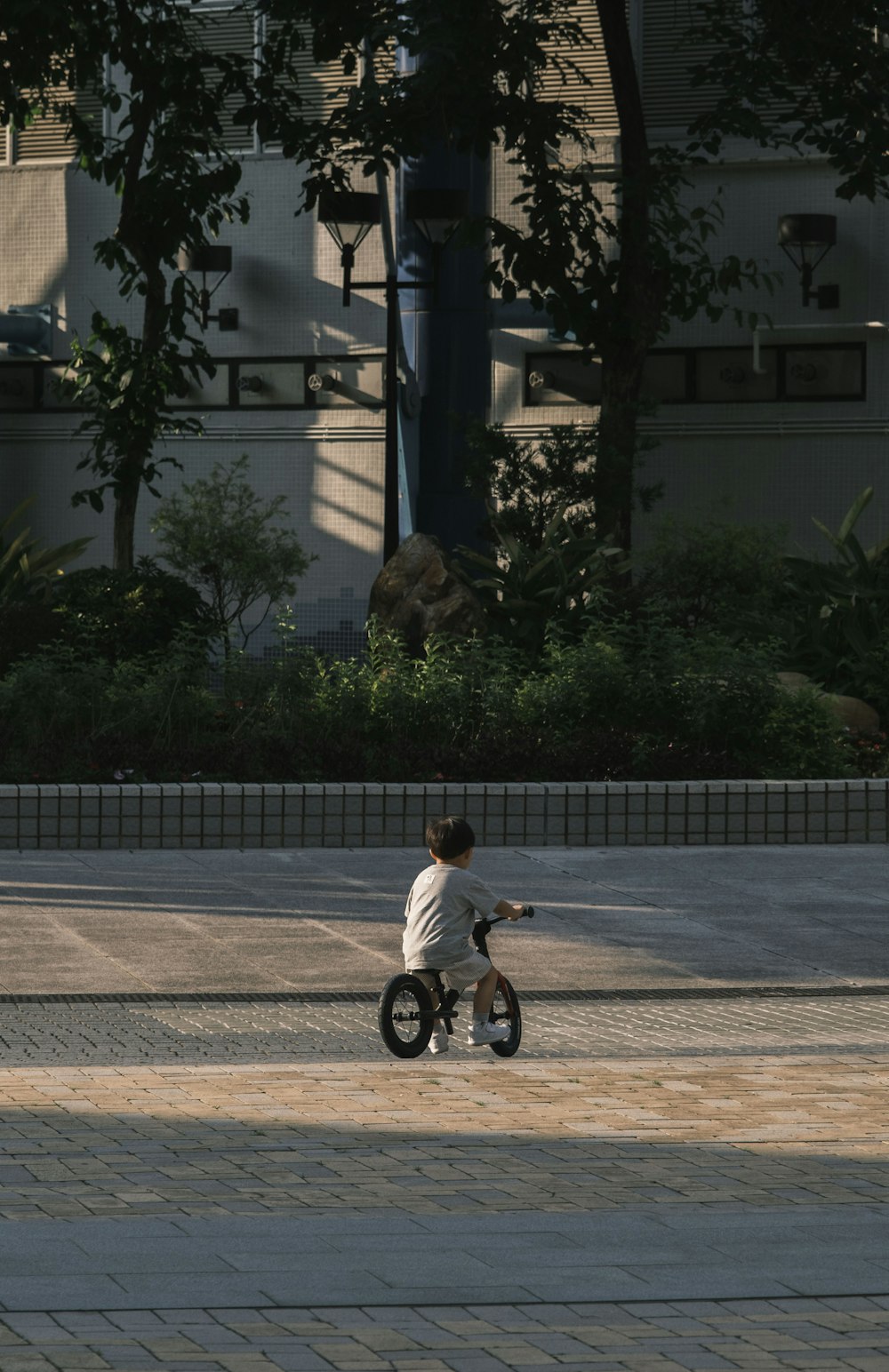a young boy riding a small bike on a sidewalk