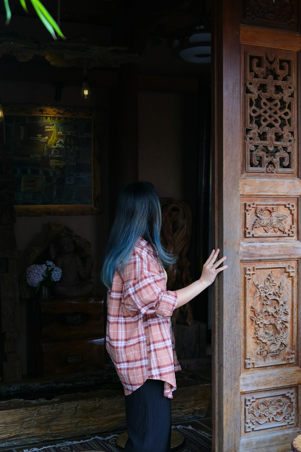 uma mulher com cabelo azul em pé em frente a uma porta de madeira