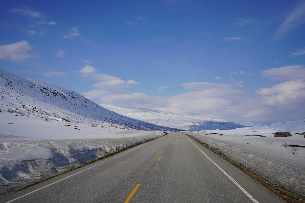 a road with snow on the ground and a mountain in the background