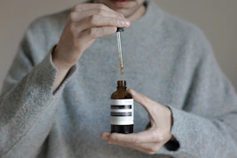 a person holding a bottle with a dropper