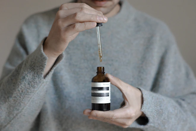a person holding a bottle with a dropper
