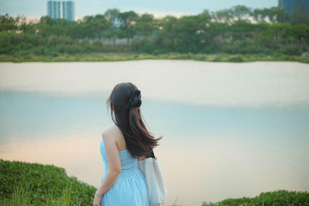 a woman in a blue dress looking at a lake