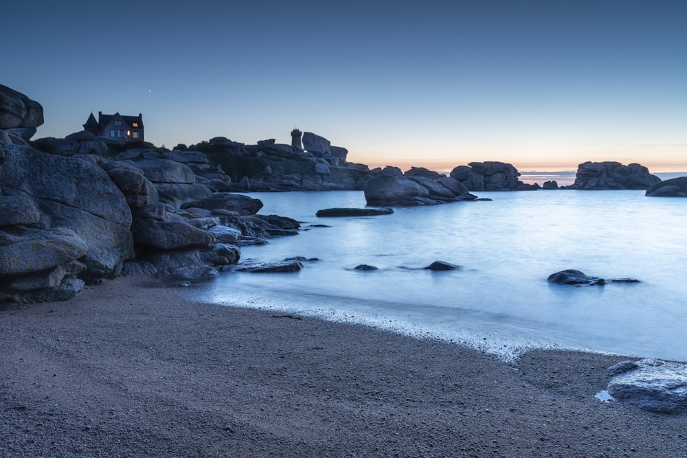a beach with rocks and water at dusk