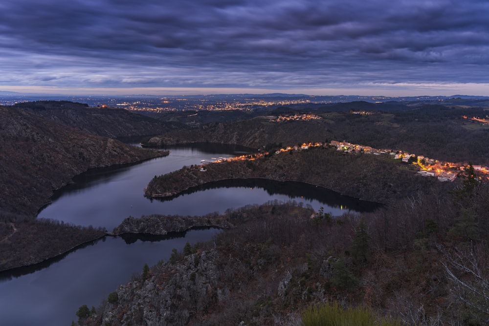 a lake surrounded by mountains under a cloudy sky